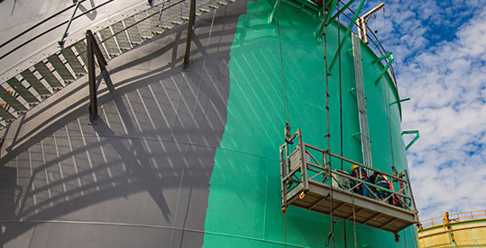 Workers applying protective coatings to a storage containe