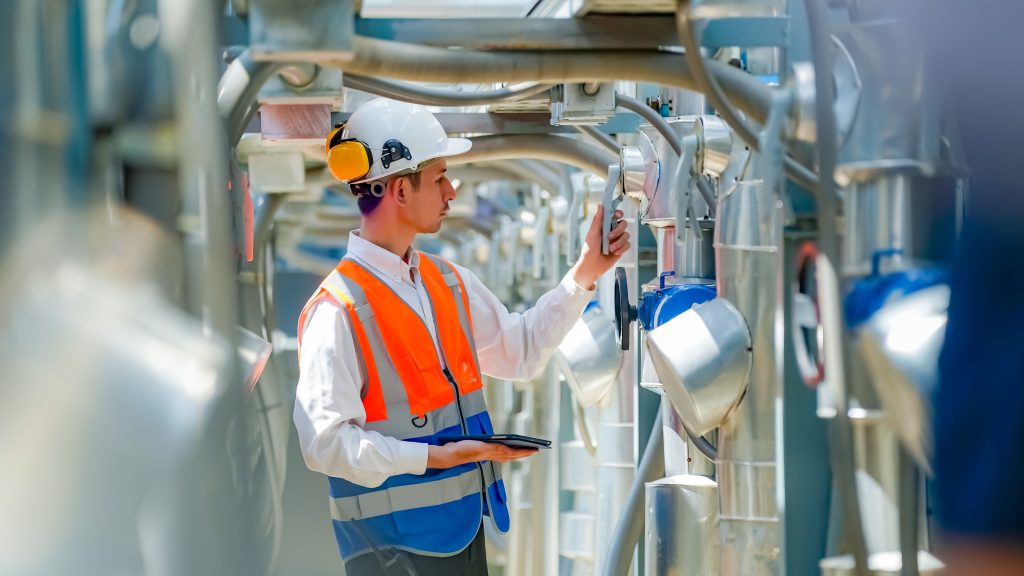 Man in hi-vis jacket using a tablet to inspect coated pipes